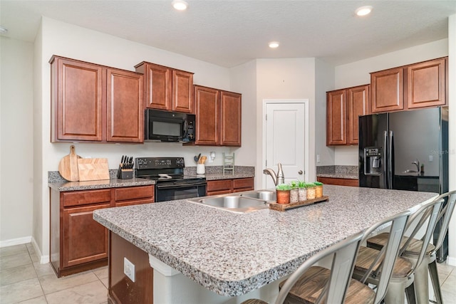 10104 Carloway Hills Dr, Wimauma, FL 33598 - kitchen with black appliances, a sink, a breakfast bar area, a center island with sink, and recessed lighting
