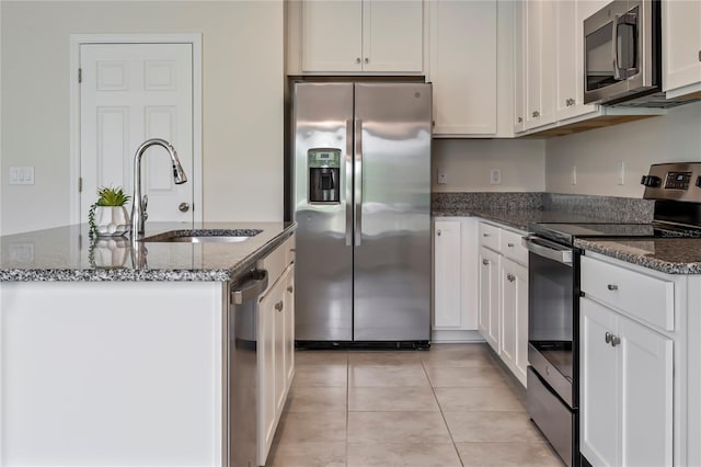 12170 Gothic Rd, Spring Hill, FL 34610 - kitchen featuring appliances with stainless steel finishes, a sink, dark stone countertops, an island with sink, and white cabinetry
