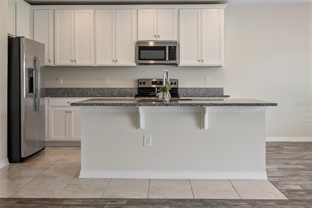 12170 Gothic Rd, Spring Hill, FL 34610 - kitchen with appliances with stainless steel finishes, a kitchen island, white cabinetry, a breakfast bar area, and baseboards