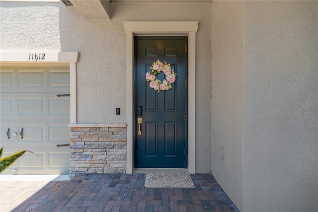 11612 Sunburst Marble Rd, Riverview, FL 33579 - doorway to property featuring stucco siding, a garage, and stone siding