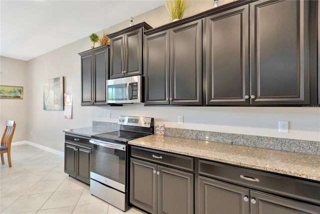 11612 Sunburst Marble Rd, Riverview, FL 33579 - kitchen featuring stainless steel appliances, baseboards, light tile patterned floors, and light stone counters