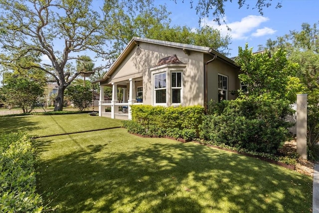 213 N Hesperides St, Tampa, FL 33609 - view of property exterior featuring a lawn, stucco siding, and covered porch