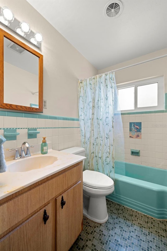 5800 3rd St S, Saint Petersburg, FL 33705 - bathroom with vanity, shower / tub combo with curtain, tile patterned floors, a wainscoted wall, and tile walls