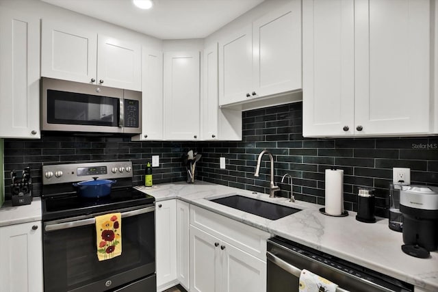 3229 40th Ln S Unit C, Saint Petersburg, FL 33711 - kitchen with stainless steel appliances, a sink, white cabinetry, and backsplash