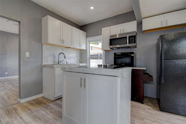 2627 17th Ave N, Saint Petersburg, FL 33713 - kitchen featuring black appliances, light wood-type flooring, white cabinets, baseboards, and light countertops