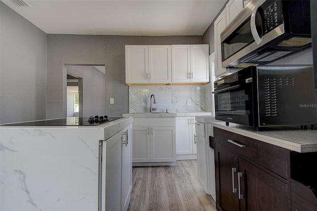2627 17th Ave N, Saint Petersburg, FL 33713 - kitchen featuring stainless steel microwave, black microwave, white cabinets, and light wood-style flooring