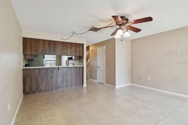 2131 Ridge Rd S Unit 3, Largo, FL 33778 - kitchen with light countertops, a ceiling fan, a textured ceiling, a peninsula, and light tile patterned floors