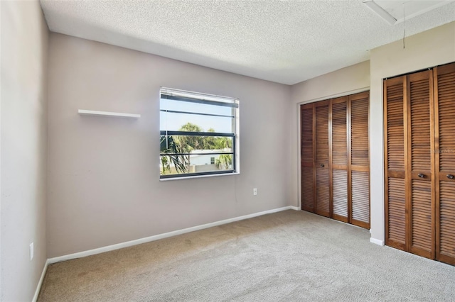 2131 Ridge Rd S Unit 3, Largo, FL 33778 - unfurnished bedroom with attic access, carpet, two closets, a textured ceiling, and baseboards