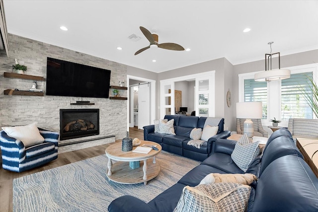 110 Carlyle Dr, Palm Harbor, FL 34683 - living area with ceiling fan, wood finished floors, a stone fireplace, crown molding, and recessed lighting
