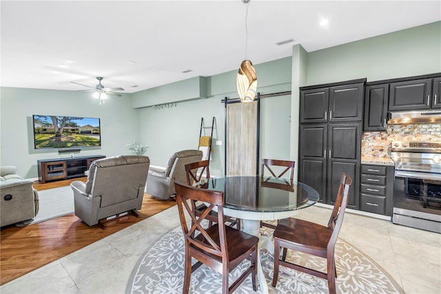 7461 Pescador Pl, Seminole, FL 33772 - dining area with ceiling fan, a barn door, and light tile patterned floors