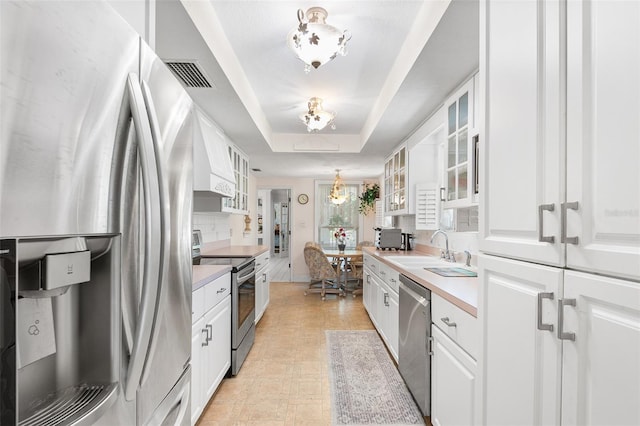 2110 Reaney Rd, Lakeland, FL 33803 - kitchen with stainless steel appliances, a chandelier, a sink, a raised ceiling, and white cabinets