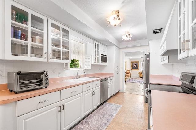 2110 Reaney Rd, Lakeland, FL 33803 - kitchen with stainless steel appliances, white cabinetry, tasteful backsplash, light countertops, and glass insert cabinets