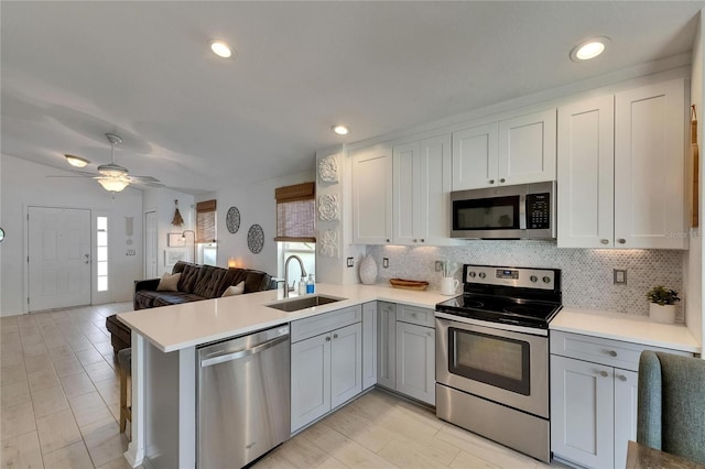 11728 Crest Creek Dr, Riverview, FL 33569 - kitchen featuring appliances with stainless steel finishes, a sink, open floor plan, a peninsula, and light countertops