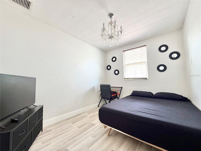 2137 W Saint Louis St, Tampa, FL 33607 - bedroom featuring light wood finished floors, a chandelier, a textured ceiling, and baseboards