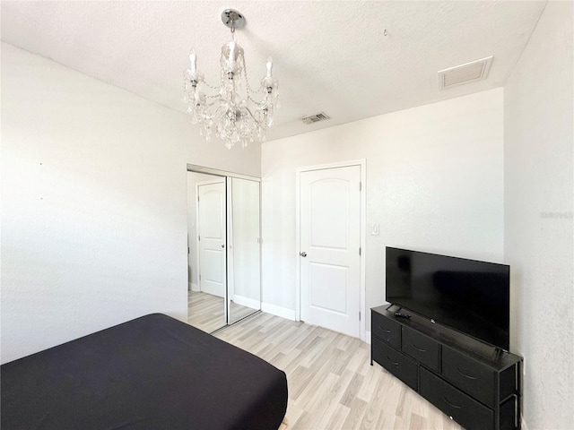 2137 W Saint Louis St, Tampa, FL 33607 - bedroom with light wood-type flooring, a chandelier, a closet, and a textured ceiling