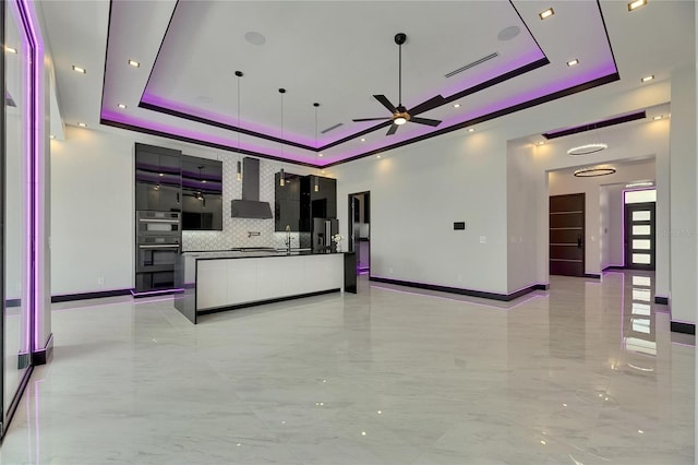 6532 Simone Shores Cir, Apollo Beach, FL 33572 - kitchen with a raised ceiling, wall chimney range hood, ceiling fan, open floor plan, and tasteful backsplash