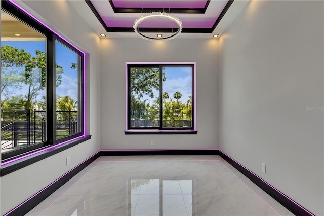 6532 Simone Shores Cir, Apollo Beach, FL 33572 - empty room featuring a raised ceiling, healthy amount of natural light, a chandelier, and baseboards