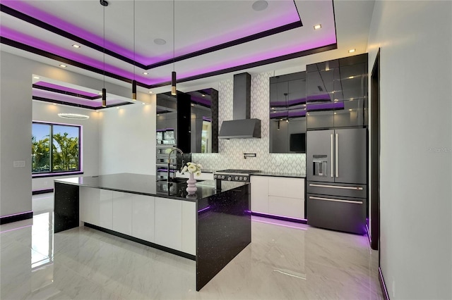 6532 Simone Shores Cir, Apollo Beach, FL 33572 - kitchen featuring wall chimney exhaust hood, modern cabinets, light marble finish floors, dark countertops, and a raised ceiling