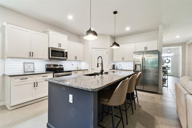 32825 Sand Creek Dr, Wesley Chapel, FL 33543 - kitchen with stainless steel appliances, a sink, backsplash, a kitchen island with sink, and a kitchen bar