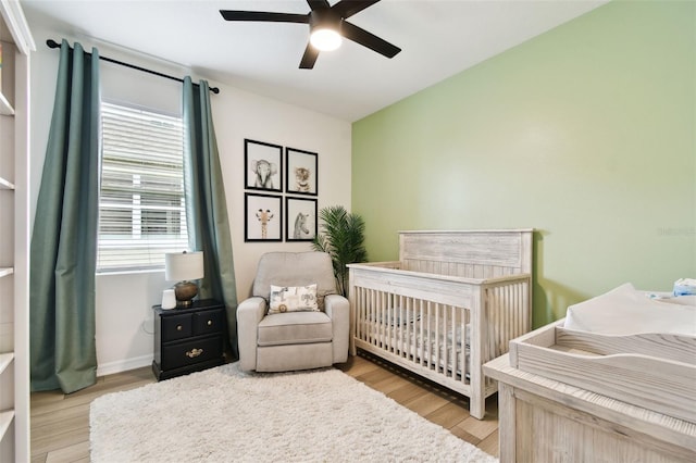 32825 Sand Creek Dr, Wesley Chapel, FL 33543 - bedroom with light wood finished floors, a crib, ceiling fan, and baseboards