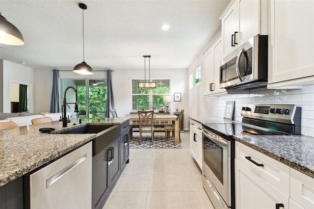 32825 Sand Creek Dr, Wesley Chapel, FL 33543 - kitchen with stainless steel appliances, tasteful backsplash, stone counters, white cabinetry, and a textured ceiling
