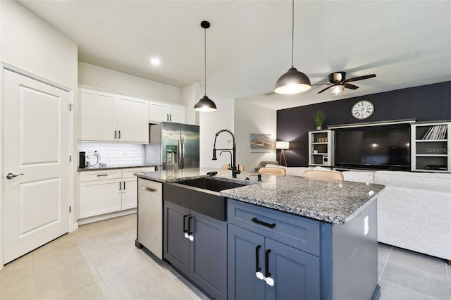 32825 Sand Creek Dr, Wesley Chapel, FL 33543 - kitchen with stainless steel appliances, a sink, light tile patterned flooring, open floor plan, and white cabinets