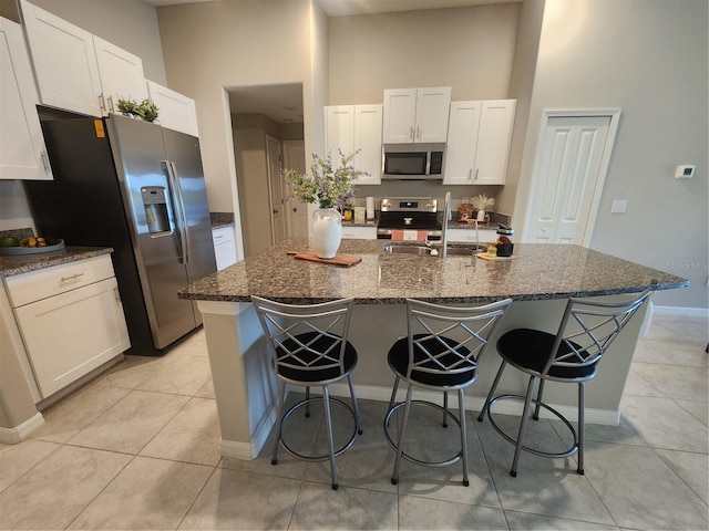 16725 Delia St, Wimauma, FL 33598 - kitchen with appliances with stainless steel finishes, a kitchen breakfast bar, white cabinets, a center island with sink, and a high ceiling