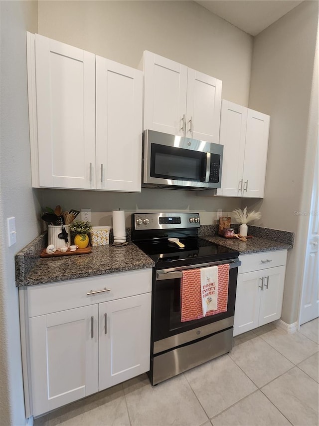 16725 Delia St, Wimauma, FL 33598 - kitchen featuring appliances with stainless steel finishes, white cabinets, dark stone countertops, and light tile patterned floors