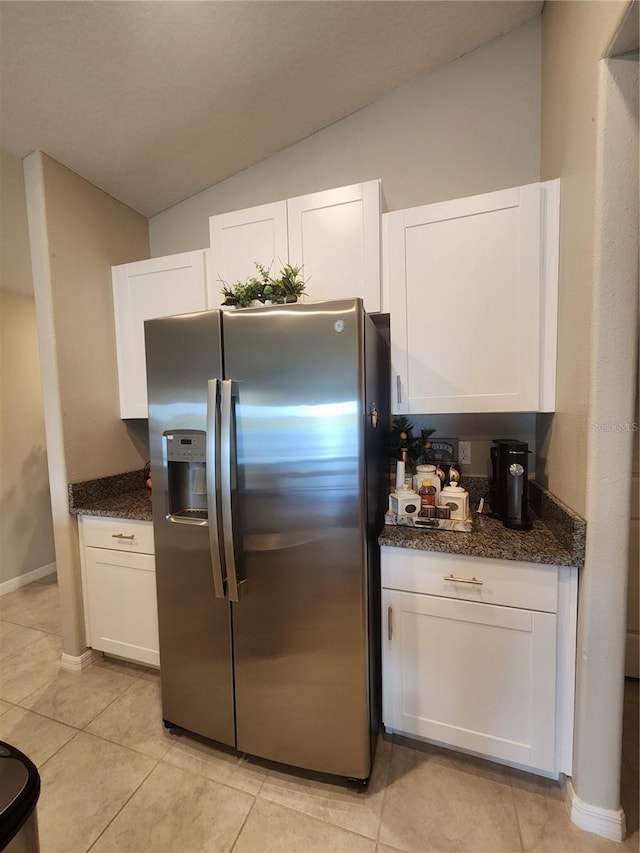16725 Delia St, Wimauma, FL 33598 - kitchen featuring stainless steel fridge, white cabinets, vaulted ceiling, light tile patterned flooring, and dark stone counters