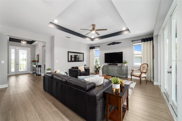 10298 SW 96th Loop, Ocala, FL 34481 - living room with a raised ceiling, ceiling fan, light wood-style floors, baseboards, and healthy amount of natural light