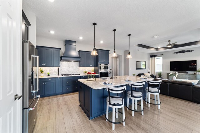 10298 SW 96th Loop, Ocala, FL 34481 - kitchen with premium range hood, open floor plan, stainless steel appliances, a kitchen breakfast bar, and light stone countertops