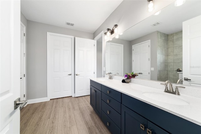 10298 SW 96th Loop, Ocala, FL 34481 - bathroom with double vanity, wood finished floors, baseboards, and tiled shower
