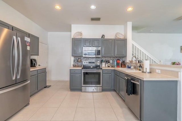 15958 Marcello Cir, Naples, FL 34110 - kitchen featuring stainless steel appliances, gray cabinetry, a sink, backsplash, and light countertops