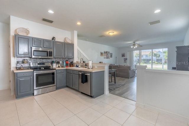 15958 Marcello Cir, Naples, FL 34110 - kitchen with appliances with stainless steel finishes, gray cabinetry, a peninsula, a sink, and tasteful backsplash