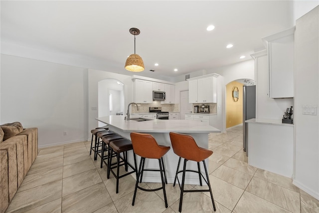 603 Loma Del Sol Dr, Davenport, FL 33896 - kitchen with arched walkways, stainless steel appliances, a breakfast bar, recessed lighting, and light countertops