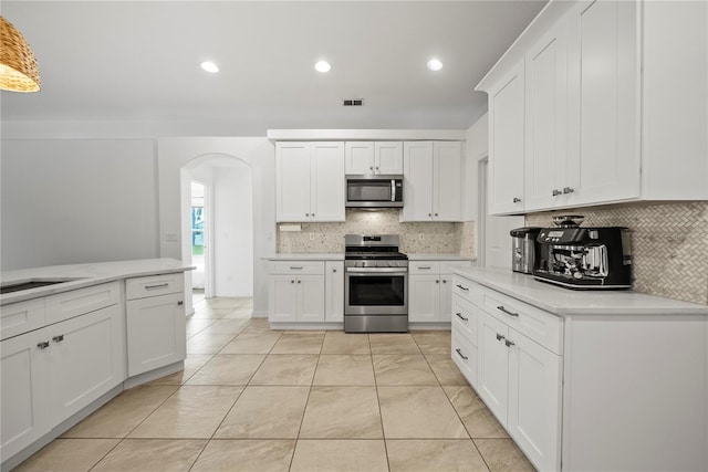 603 Loma Del Sol Dr, Davenport, FL 33896 - kitchen featuring stainless steel appliances, arched walkways, decorative backsplash, light countertops, and recessed lighting