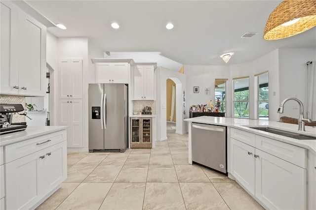 603 Loma Del Sol Dr, Davenport, FL 33896 - kitchen with appliances with stainless steel finishes, arched walkways, backsplash, white cabinetry, and light countertops