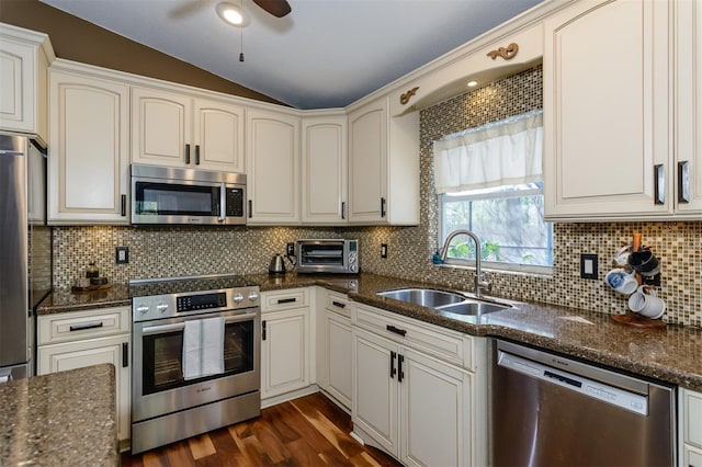 5619 Essex Ct, Palm Harbor, FL 34685 - kitchen featuring stainless steel appliances, a sink, vaulted ceiling, tasteful backsplash, and dark stone counters