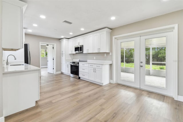 1110 Canal St, Ruskin, FL 33570 - kitchen featuring appliances with stainless steel finishes, a sink, french doors, white cabinets, and light wood-type flooring