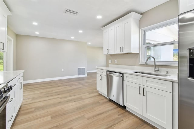 1110 Canal St, Ruskin, FL 33570 - kitchen with appliances with stainless steel finishes, a sink, baseboards, white cabinets, and light wood-type flooring