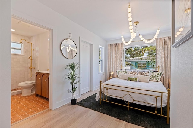 1579 Bayshore Blvd, Dunedin, FL 34698 - bedroom with wood finished floors, a chandelier, connected bathroom, and baseboards