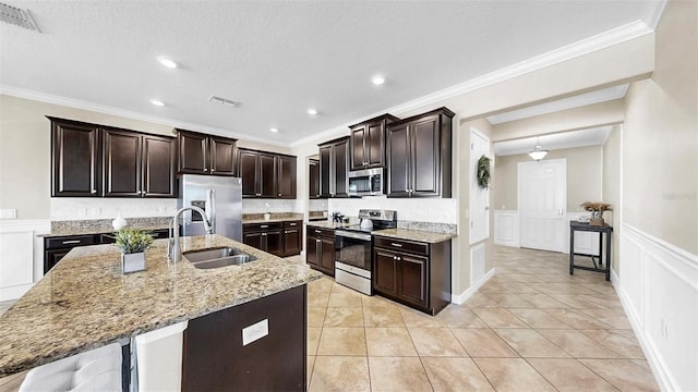 13903 Sage Thrasher Ln, Riverview, FL 33579 - kitchen with appliances with stainless steel finishes, a decorative wall, light stone counters, crown molding, and an island with sink