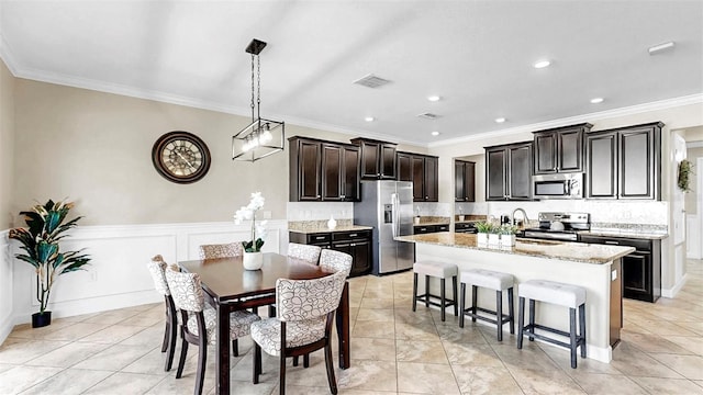 13903 Sage Thrasher Ln, Riverview, FL 33579 - kitchen featuring stainless steel appliances, a breakfast bar, tasteful backsplash, a center island, and crown molding