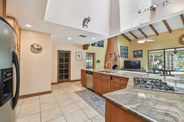 7507 Beasley Rd, Tampa, FL 33615 - kitchen with stainless steel appliances, a sink, brown cabinetry, light tile patterned floors, and high vaulted ceiling