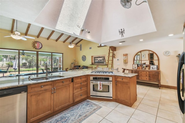 7507 Beasley Rd, Tampa, FL 33615 - kitchen with appliances with stainless steel finishes, a sink, a ceiling fan, high vaulted ceiling, and brown cabinetry