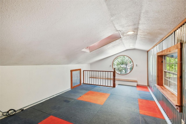 7507 Beasley Rd, Tampa, FL 33615 - additional living space featuring a skylight, a textured ceiling, rubber floors, vaulted ceiling, and baseboards