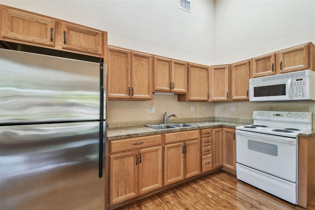 7507 Beasley Rd, Tampa, FL 33615 - kitchen with white appliances, a sink, light wood-style floors, brown cabinets, and a towering ceiling