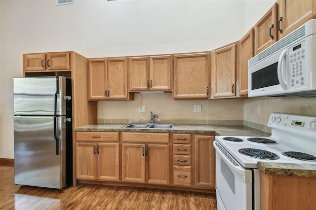 7507 Beasley Rd, Tampa, FL 33615 - kitchen with white appliances, a sink, light wood finished floors, and brown cabinets