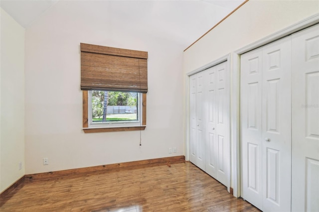 7507 Beasley Rd, Tampa, FL 33615 - unfurnished bedroom featuring two closets, wood finished floors, baseboards, and lofted ceiling