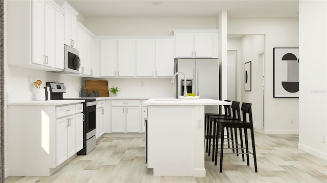 12597 Lily Quartz Loop, Parrish, FL 34219 - kitchen with appliances with stainless steel finishes, a kitchen island with sink, light wood-type flooring, white cabinetry, and a kitchen breakfast bar